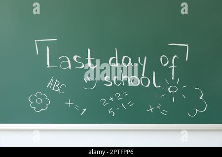 Tableau noir avec texte LE DERNIER JOUR DE L'ÉCOLE et dessins sur le mur blanc Banque D'Images