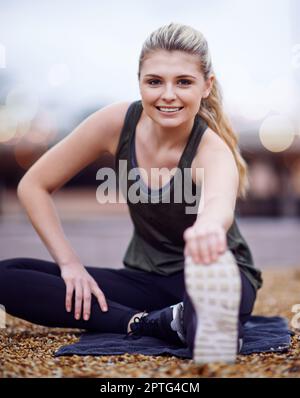 A été ravivé pour cette course. une jeune femme qui s'étire les jambes avant une course Banque D'Images