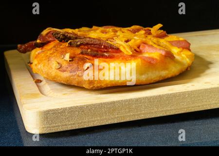 La pizza avec saucisse et fromage sur fond noir. Cuisson sur table. Produits de l'alimentation Banque D'Images