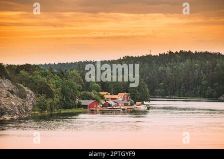 Suède.Beaucoup de belles chalets en bois rouge suédois Maisons sur la côte des îles Rocheuses en soirée d'été.Paysage de lac ou de rivière. Banque D'Images