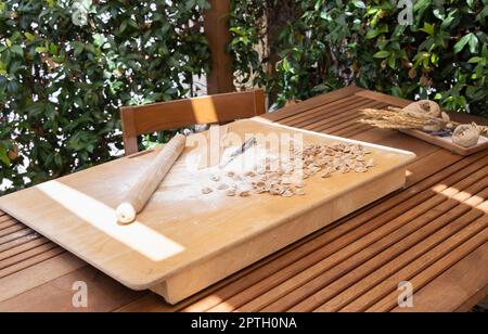 Préparer des pâtes italiennes du sud orecchiette en plein air dans la cour de la maison de près. Pâtes maison fraîches traditionnelles de la région des pouilles. Régime méditerranéen i Banque D'Images