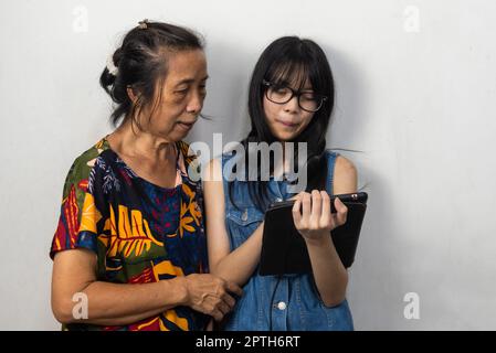 Les jeunes femmes asiatiques enseignent aux femmes plus âgées comment utiliser les tablettes modernes de technologie Internet. Banque D'Images