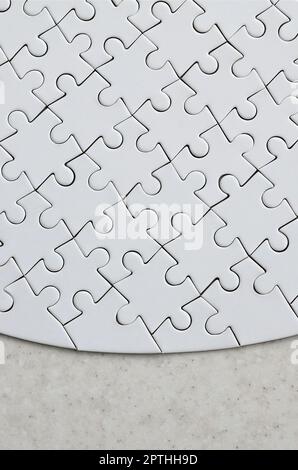 Un puzzle blanc de forme complète repose sur une surface en pierre traitée. Image texturée avec espace de copie