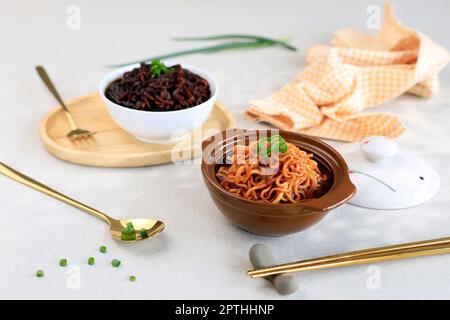 Ramyeon épicé au Kpran et Jjajangmyeon à la sauce noire, servi sur un bol en céramique avec cuillère dorée et fourchette Banque D'Images