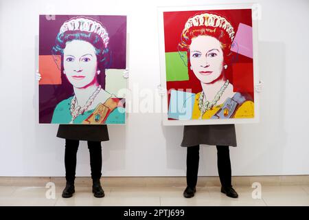 Photo du dossier datée du 26/03/21, de techniciens de la galerie avec (à gauche) la reine Elizabeth II, de: Réalignement de l'imprimé Queens en couleurs par Andy Warhol et (à droite) la reine Elizabeth II, de: Réalignement de l'imprimé Queens (édition royale) en couleurs par Andy Warhol à Christie's dans le centre de Londres. La reine Elizabeth II avait commandé plusieurs tableaux officiels de portrait royal pendant ses 70 ans de règne et le roi Charles III est sur le point de suivre ses traces, avec un portrait pour commémorer son couronnement. Date de publication : vendredi 28 avril 2023. Banque D'Images