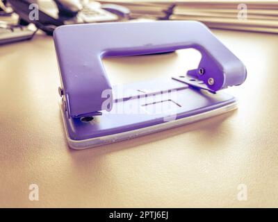 Punch de bureau en métal bleu pour perforer les trous dans les feuilles de papier et les documents sur la table de travail dans le bureau. Papeterie. Banque D'Images