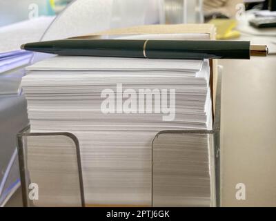 Petits morceaux de papier carrés pour les notes et les notes sur le bureau et un stylo à bille vert. Travail d'entreprise. Banque D'Images