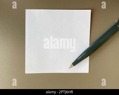 Petits morceaux de papier carrés pour les notes et les notes sur le bureau et un stylo à bille vert. Travail d'entreprise. Banque D'Images