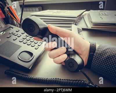 Gros plan d'un homme d'affaires tenant le combiné d'Un téléphone fixe noir. Banque D'Images