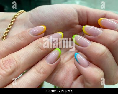 Manucure multicolore colorée sur les ongles courts sur fond jaune.Nail art.Rose, vert, jaune, vernis à ongles pêche. Banque D'Images