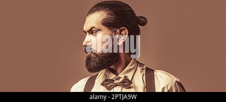 Portrait de beau barbu homme en chemise blanche et noeud papillon, bretelles. Homme de barbe en noeud papillon et bretelles. Homme en chemise corrigeant sa couleur Banque D'Images