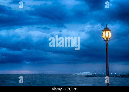 Poste de lumière au nigth près de la mer avec fond de stom Banque D'Images