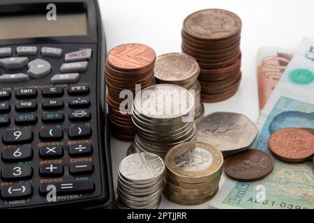 Piles de pièces et de billets de banque britanniques avec calculatrice Banque D'Images