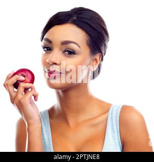 Tout est possible si vous faites de l'exercice et mangez sainement. Une jeune femme en tenues de gymnastique tenant une pomme et souriant à la caméra Banque D'Images