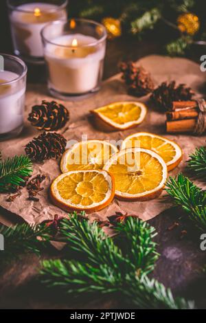 Épices de Noël et d'orange séchées avec branches d'arbre de noël, cannelle, bougies sur la table de cuisine Banque D'Images