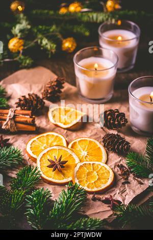 Épices de Noël et d'orange séchées avec branches d'arbre de noël, cannelle, bougies sur la table de cuisine Banque D'Images