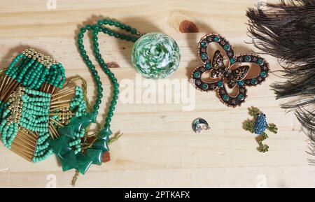 Plumes de paon avec perles vertes et brocher de papillons de cuivre et de vert sur table en bois Banque D'Images