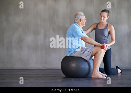 Aider mes patients à récupérer est ma seule priorité. un thérapeute physique travaillant avec un homme âgé Banque D'Images