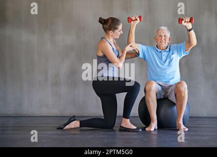 Aider mes patients à récupérer est ma seule priorité. un thérapeute physique travaillant avec un homme âgé Banque D'Images