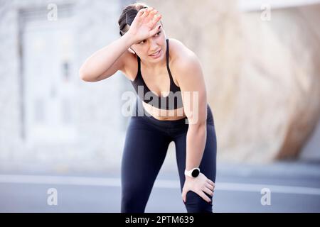 Fitness, fatiguée et transpirante avec une femme de sport essuyant son front après avoir été en plein air dans la ville pour le cardio. Route, exercice et entraînement avec une femme Banque D'Images