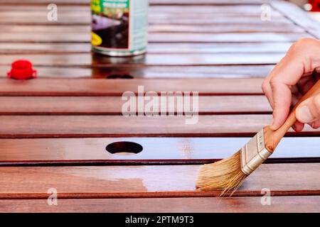 Le vernis protège le bois du jardin des fissures, de la peinture à l'huile de teck. Banque D'Images