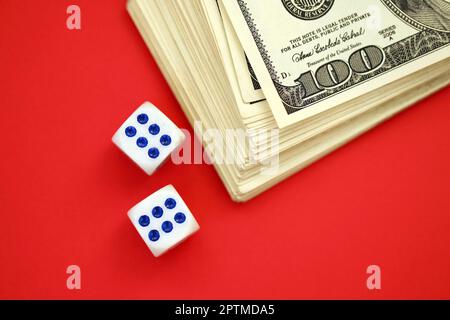 Concept d'argent, de finance et de jeu. Gros plan sur une centaine de billets américains et deux dés blancs en haut montrant les chiffres six et six Banque D'Images