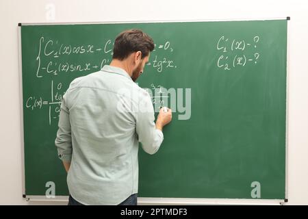 Professeur mature expliquant les mathématiques au tableau noir en classe Banque D'Images