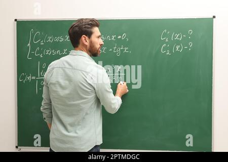 Professeur mature expliquant les mathématiques au tableau noir en classe Banque D'Images