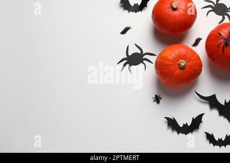 Composition de pose plate avec citrouilles, chauves-souris en papier et araignées sur fond blanc, espace pour le texte. Fête d'Halloween Banque D'Images