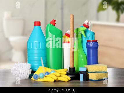 Différentes fournitures de nettoyage de toilettes sur une table en bois dans la salle de bains Banque D'Images