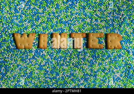 Hiver. Le mot des lettres comestibles de Cracker se trouve sur la poudre émaillée. Un grand nombre de perles douces et colorées de très petite taille pour la décoration o Banque D'Images