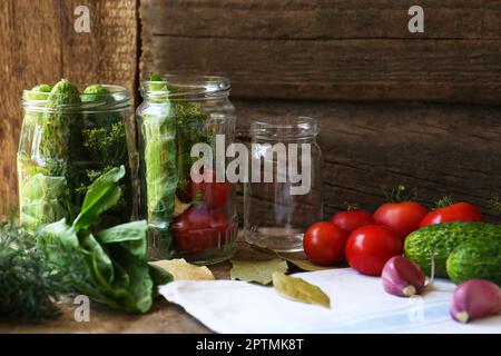 Pots en verre, légumes frais et herbes sur table en bois. Recette de pickling Banque D'Images