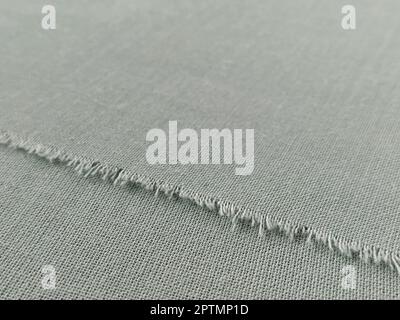 Bord déchiré de tissu laineux fin en vert ou bleu. Fils lâches sur le bord d'un morceau de textile. Gros plan. Arrière-plan tissé. Col vert pastel calme Banque D'Images