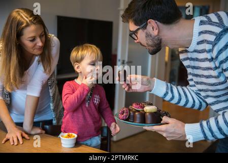 Père offrant une pâtisserie à son petit fils, Munich, Allemagne Banque D'Images