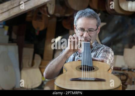 Artisan examinant la guitare à l'atelier Banque D'Images
