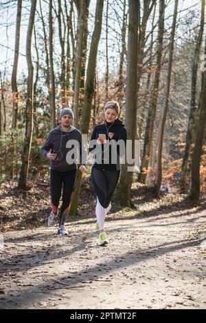 Homme et femme qui font du jogging sur un sentier de remise en forme en forêt Banque D'Images