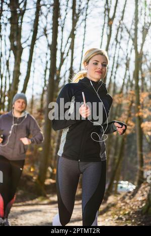 Homme et femme qui font du jogging sur un sentier de remise en forme en forêt Banque D'Images