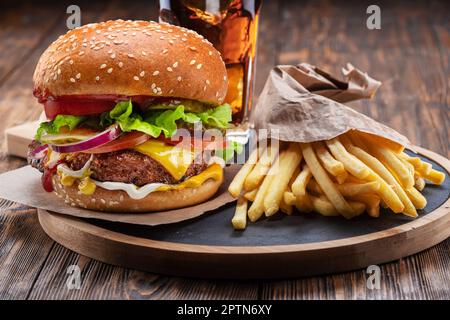 Cheeseburger ou hamburger savoureux, verre de cola et frites sur plateau en bois gros plan. Banque D'Images