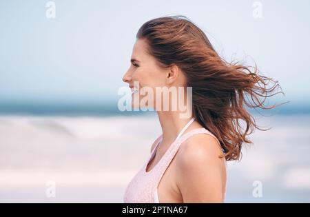 J'adore la brise fraîche. une femme attrayante appréciant une journée à la plage Banque D'Images