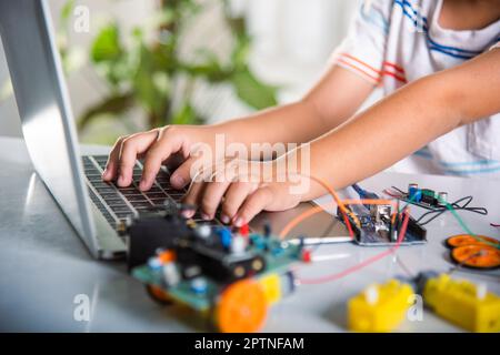 Un enfant asiatique apprend le codage et la programmation avec un ordinateur portable pour la voiture robot Arduino, les enfants qui tapent le code dans un ordinateur avec un jouet de voiture, UN duca À VAPEUR Banque D'Images