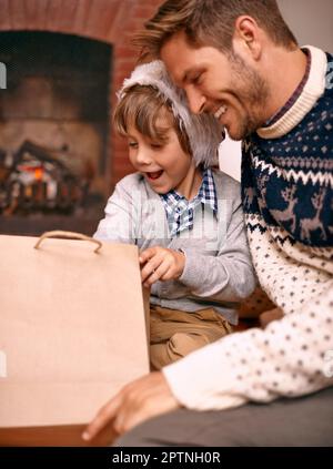 L'heure des cadeaux. Un garçon et son père assis avec un cadeau la veille de Noël Banque D'Images