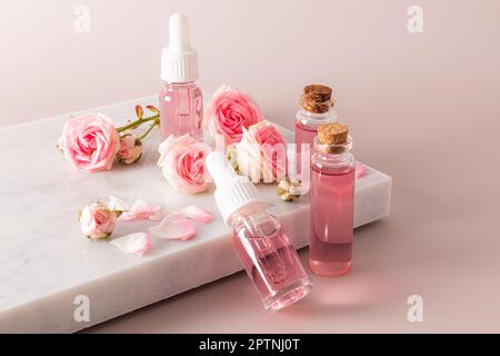 cosmétiques en bouteilles avec bouchon blanc et pipette, prbka sur un podium en marbre blanc et fond rose. Léger et doux, auto-entretien Banque D'Images