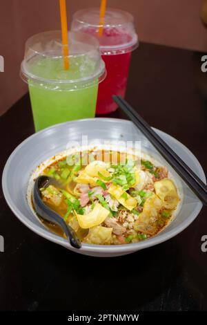 Nouilles jaunes aux œufs dans une soupe épicée de porc, photo de stock Banque D'Images