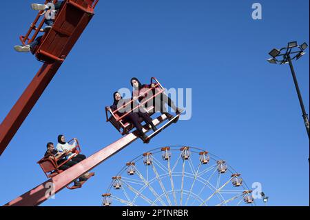 PALESTINE, Jenin, les gens apprécient une foire après la fin du Ramadan, les gens dans le carrousel, derrière la roue de Ferris à une foire / PALÄSTINA, Jenin, Jahrmarkt Freuden nach dem Ende des Ramadan Fastenmonat Banque D'Images