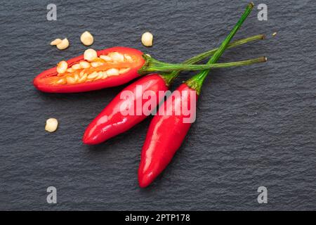 Piment ou poivrons rouges chauds sur une assiette d'ardoise noire en pierre naturelle. Pose à plat. Banque D'Images