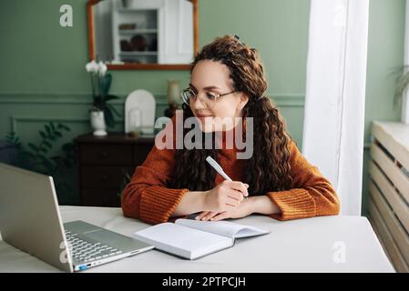 Apprentissage et travail à distance : jeunes étudiantes étudiant en ligne avec un ordinateur portable au bureau à domicile. Éducation en ligne efficace: Jeune étudiante féminine Banque D'Images