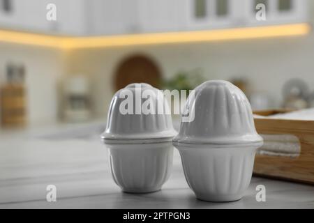 Salières et poivrières en céramique sur une table en marbre blanc dans la cuisine Banque D'Images