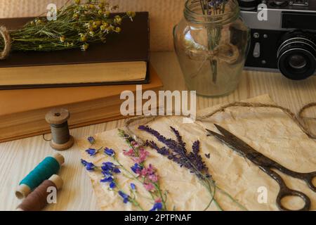 Composition avec de belles fleurs séchées et du papier sur une table en bois Banque D'Images