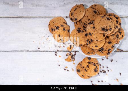 Pile et assiette de biscuits aux pépites de chocolat. Le chocolat américain traditionnel dépose des biscuits croustillants sur fond de bois blanc, espace de copie Banque D'Images