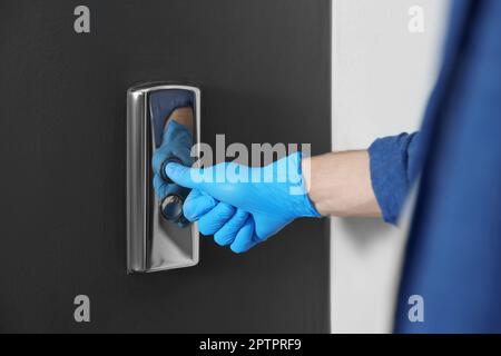 Homme dans le gant en appuyant sur le bouton d'appel de l'ascenseur, gros plan. Mesure de protection Banque D'Images